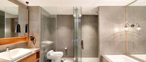 Ein modernes Badezimmer mit einer gläsernen Duschkabine, einer großzügigen Badewanne und einem Waschtisch mit Waschbecken und Spiegel.