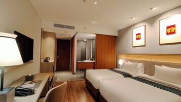 A hotel room with a bed, bedside table, lamp, and a desk with a telephone.