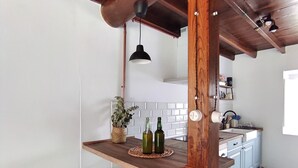 Une cuisine dotée d’un îlot central en bois, de deux tabourets de bar, d’un luminaire suspendu et d’un sol à motifs.