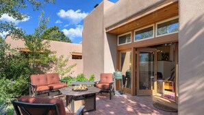 An outdoor patio with a fire pit, two brown leather chairs, and a table. - Stylish and Serene, Community Pool (Santa Fe)