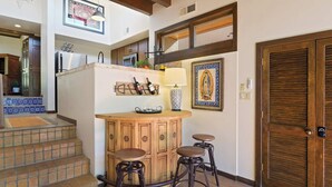 A kitchen with wooden cabinets, a built-in wine rack, and a bar area with stools. - Stylish and Serene, Community Pool (Santa Fe)