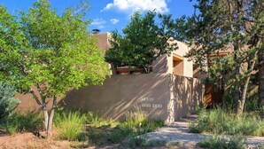 A building with a stucco exterior, a paved pathway, and a mailbox with the number 232432. - Stylish and Serene, Community Pool (Santa Fe)