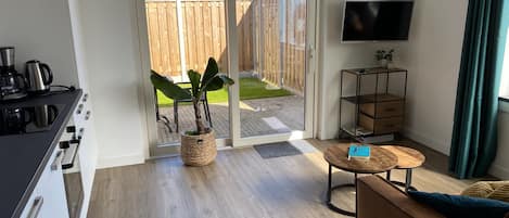 A modern living room with a sofa, a coffee table, a TV, and a potted plant.