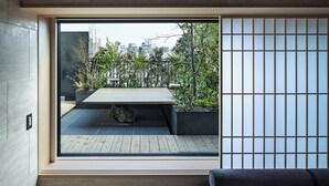 A modern interior with a large window, a wooden bench, and a view of a cityscape. - Hotel tou nishinotoin kyoto (Kyoto)