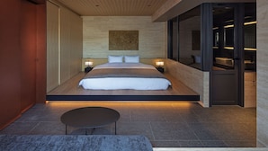 A modern bedroom with a large bed, bedside lamps, a small table, and a view of the bathroom. - Hotel tou nishinotoin kyoto (Kyoto)