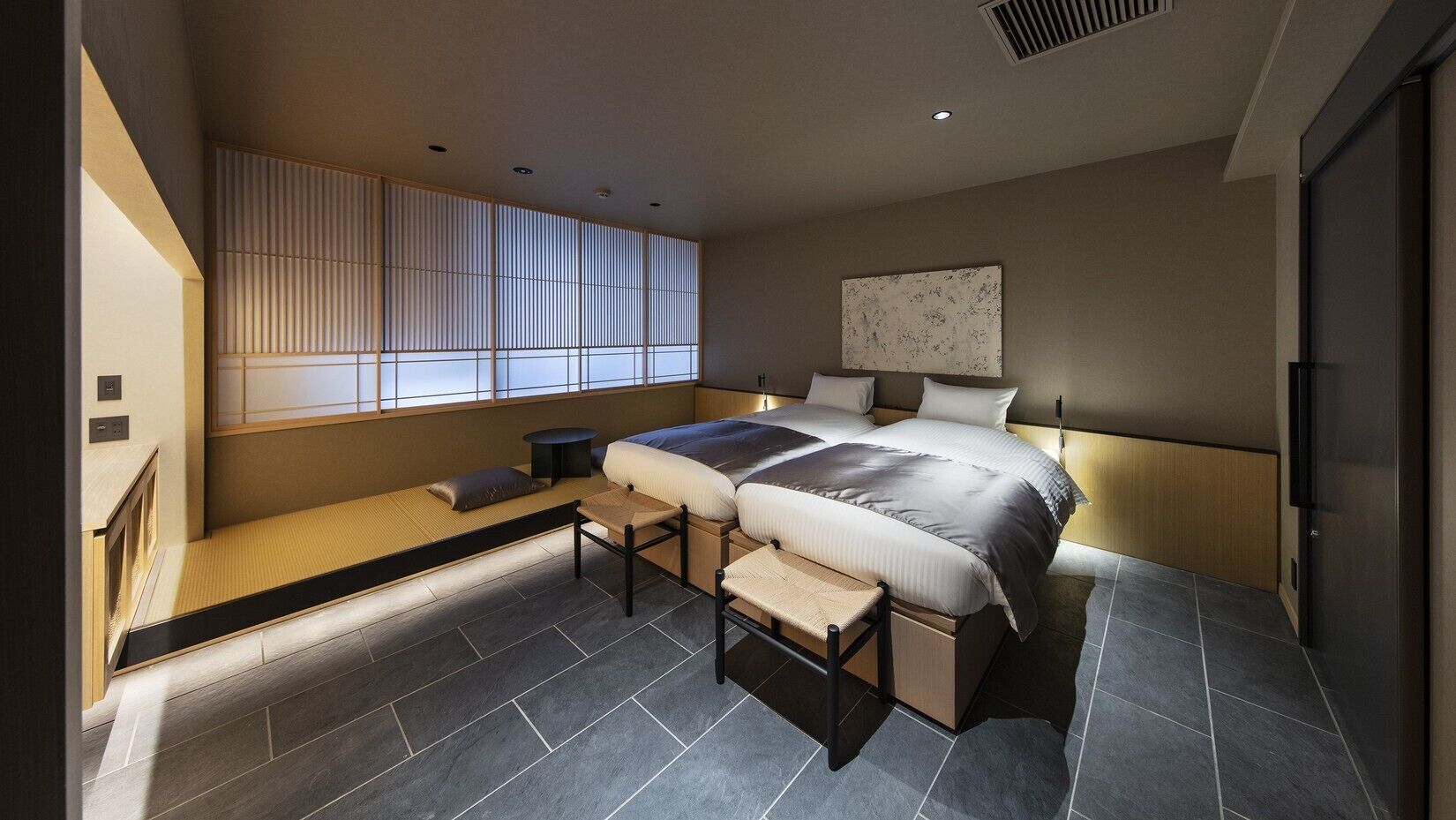 A modern bedroom with a bed, bedside tables, a window with blinds, a wall-mounted artwork, and a built-in bench with storage.