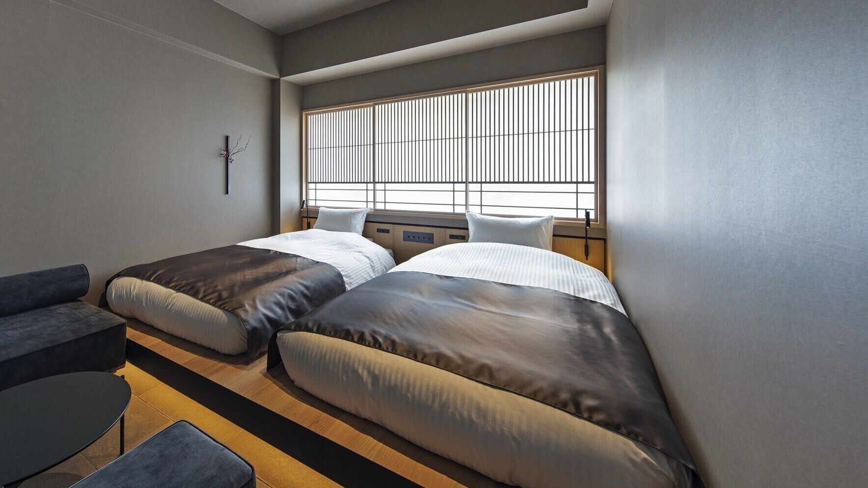 A compact room with two beds, a sofa, and a small table.