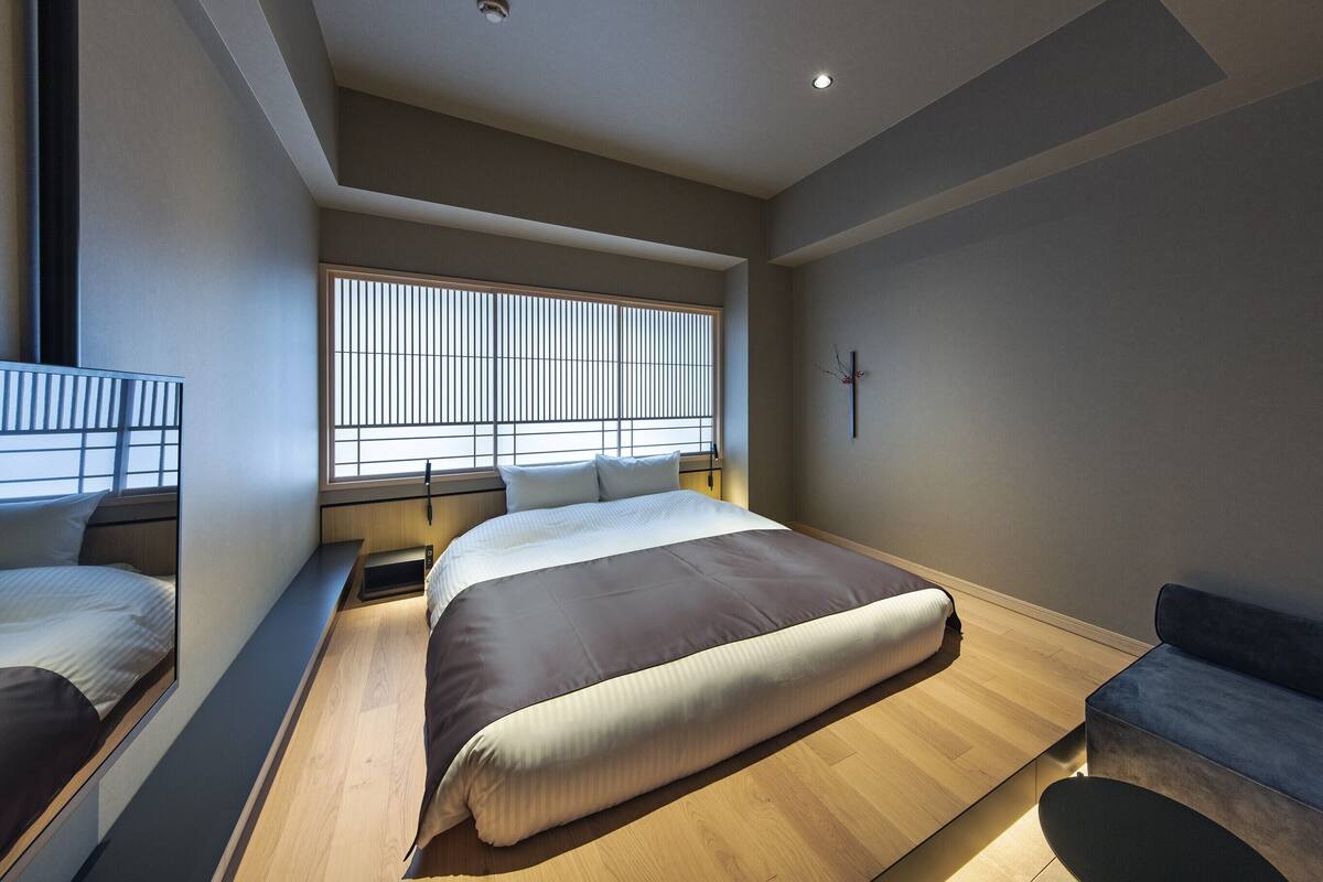 Un dormitorio moderno con una cama grande, un banco y un sofá.