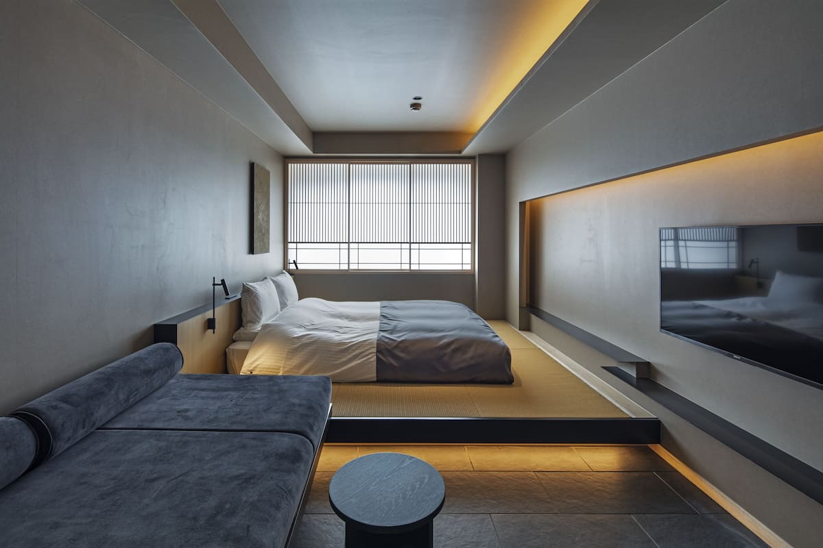 Un dormitorio moderno con cama, sofá y televisión.