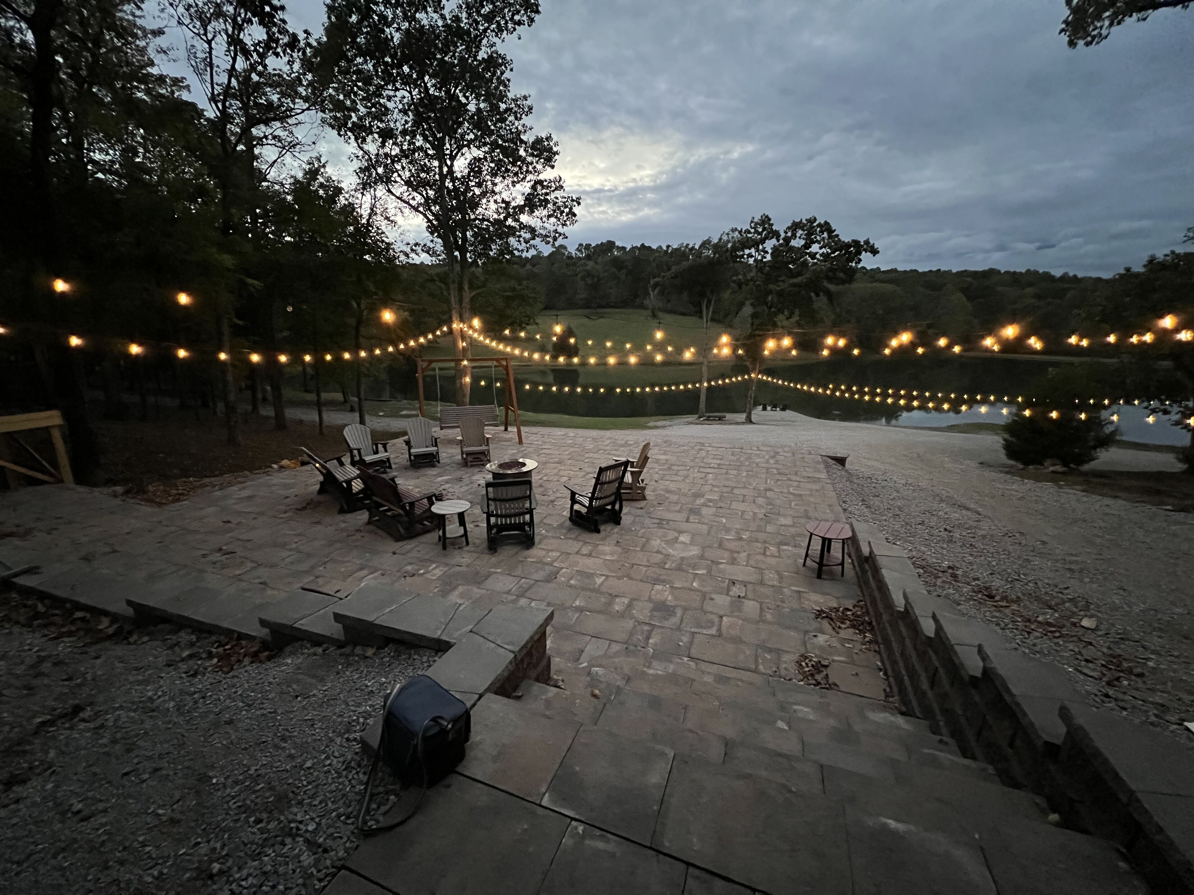 Une terrasse extérieure avec un sol en pierre, des sièges et des guirlandes lumineuses.