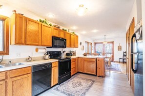A spacious kitchen with wooden cabinets, a microwave, stove, and dishwasher.