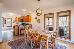 A spacious kitchen with wooden cabinets, a dining area with a table and chairs, and a large window providing a view of the outdoors. - Timberly - Hot Tub, Dog Friendly, Lake Privileges (Davis)