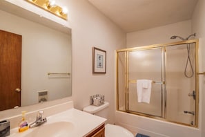 A bathroom with a large mirror, a sink, a toilet, and a glass-enclosed shower. - Timberly - Hot Tub, Dog Friendly, Lake Privileges (Davis)