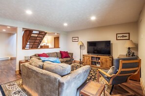 A living room with a sofa, a television, a bookshelf, and a chair.
