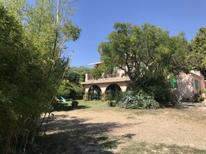 A villa with a garden, a pool, and a view of the surrounding landscape.