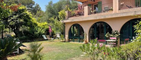 A two-story building with a covered patio, outdoor seating, and a garden area with potted plants.