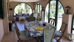 Un comedor con una mesa dispuesta para cuatro personas, rodeado de sillas de mimbre.