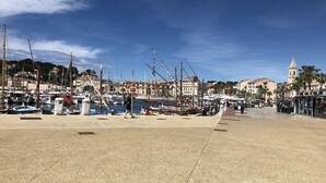 Un puerto deportivo con barcos amarrados, un paseo marítimo y edificios al fondo.