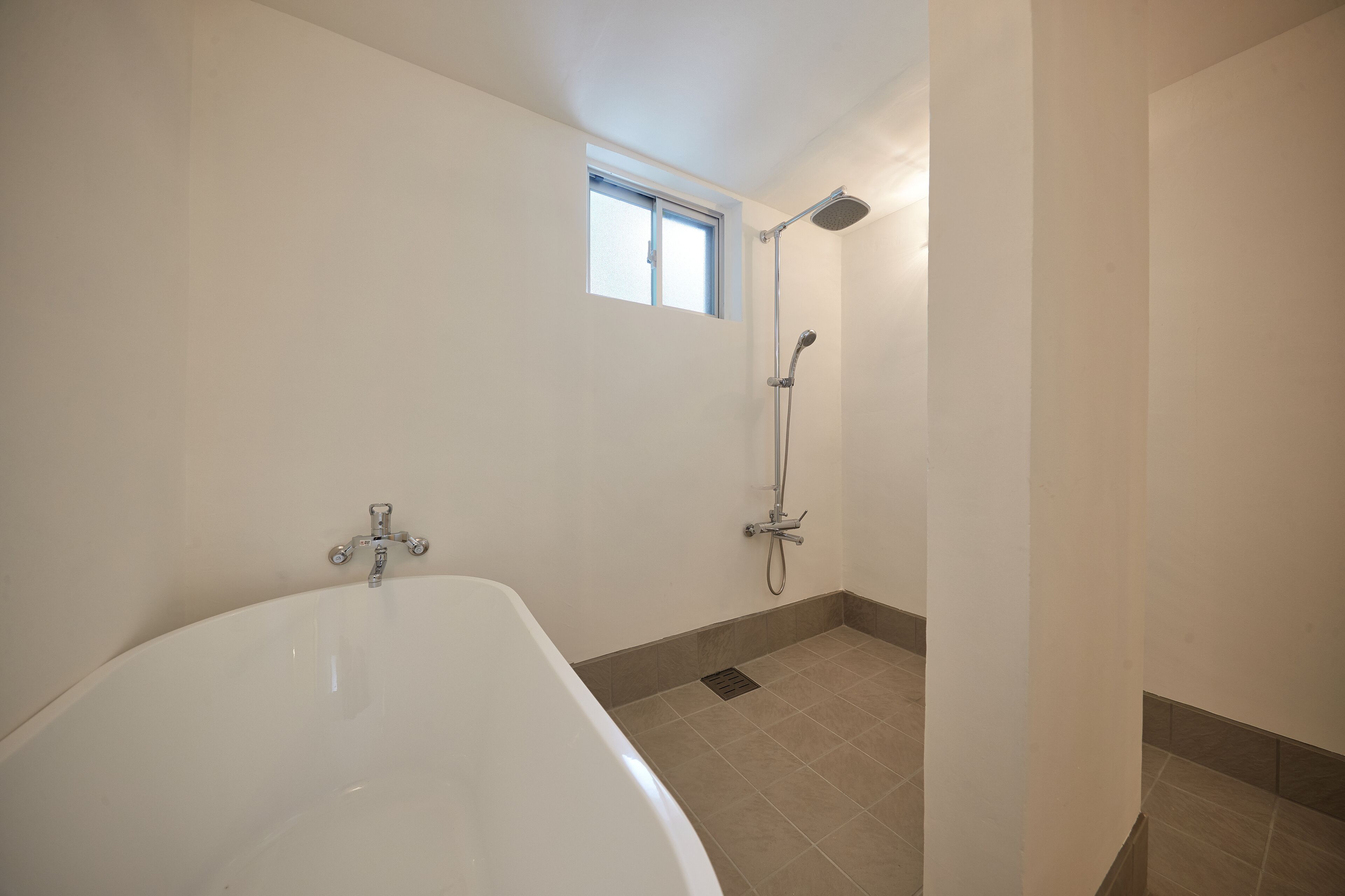 A bathroom with a bathtub, a shower, and a window.