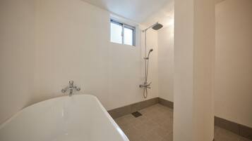 A bathroom with a bathtub, a shower, and a window.