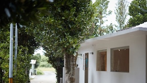 A pathway leading to a building with a white exterior, a door, and windows. - Adan Resort EN (Motobu)
