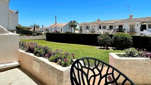 A courtyard with a lawn, a hedge, and a row of white buildings with red-tiled roofs. - RIVIERA PLAYA 200m to the beach in Riviera del Sol (Mijas Costa)