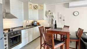 A modern kitchen with white cabinets, a built-in oven, and a dining area with wooden chairs and a table. - RIVIERA PLAYA 200m to the beach in Riviera del Sol (Mijas Costa)
