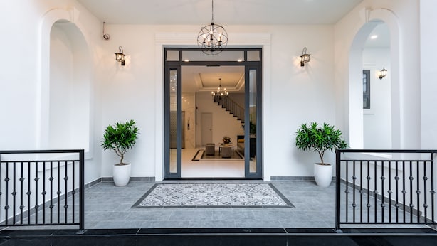 Une entrée moderne avec une porte en verre, un escalier et des plantes en pot.