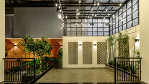 Un vaste espace intérieur avec un mur en briques, des plantes en pot et un sol carrelé.