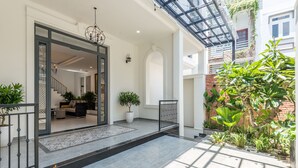 Une entrée moderne avec une porte en verre, un escalier menant à l’intérieur et un petit jardin agrémenté de plantes en pot.