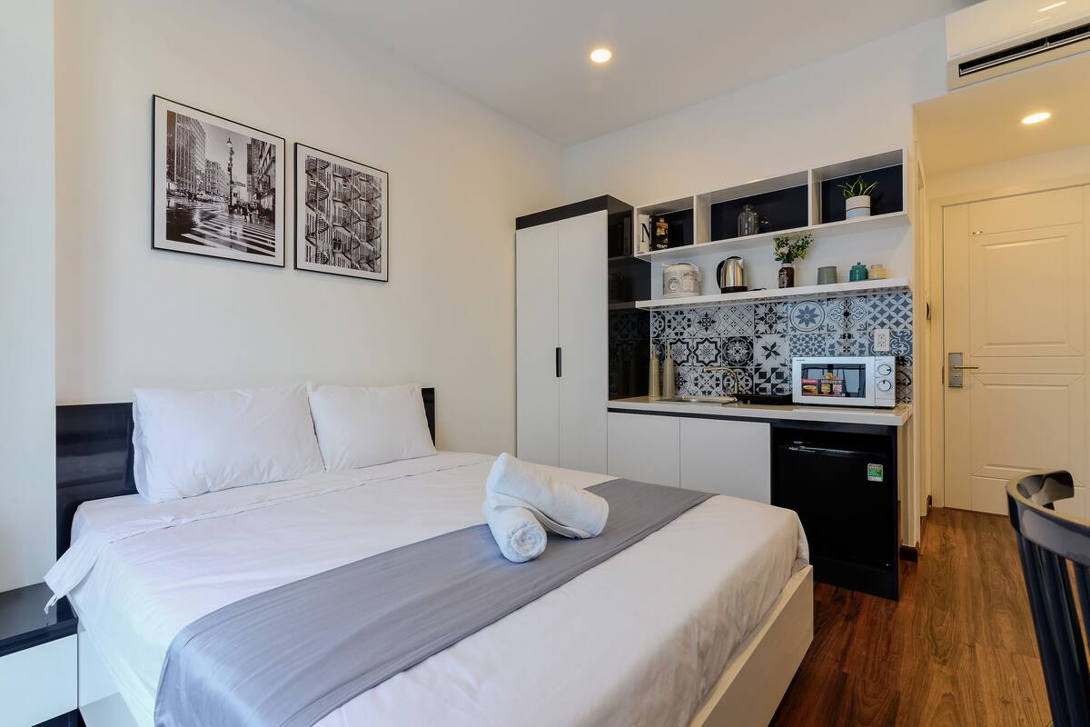 Ein Hotelzimmer mit Bett, einer kleinen Küchenzeile und zwei gerahmten Bildern an der Wand.