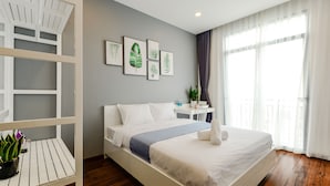 Une chambre d’hôtel moderne avec un grand lit, une étagère blanche et une petite table sur laquelle est posée une plante.