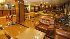 A hotel lobby with leather sofas, a reception desk, and a wheelchair. - Met Gold Hotel (Gaziantep)