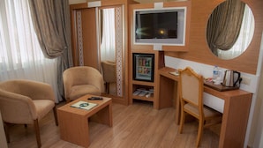 A hotel room with a TV, a mini-fridge, a coffee maker, and two armchairs. - Met Gold Hotel (Gaziantep)