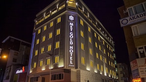 A multi-story hotel with illuminated signage, a prominent entrance, and a corner location with adjacent buildings. - Met Gold Hotel (Gaziantep)
