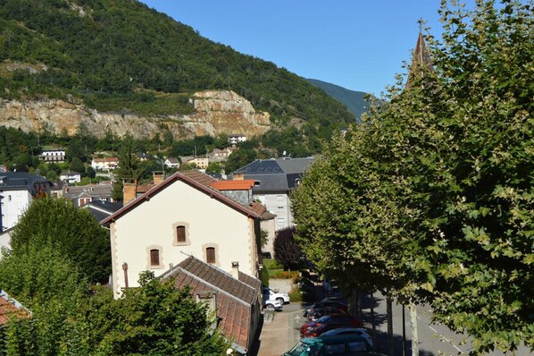 A town with buildings, a mountain, and parked cars. - Hôtel-Bar Le Bellevue (Ax-les-Thermes)