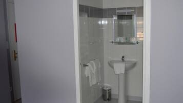 A bathroom with a glass shower enclosure, a pedestal sink, and a mirror above it.