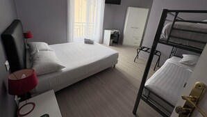 Hotellihuoneessa on yksi sänky, työpöytä tuolilla, kerrossänky, vaatekaappi ja seinälle asennettu televisio.