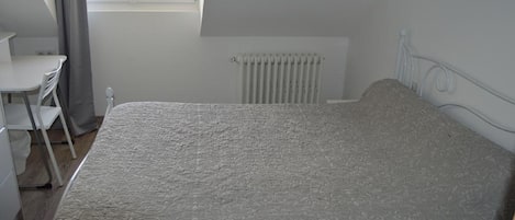 A bedroom with a bed, a desk, and a chair.