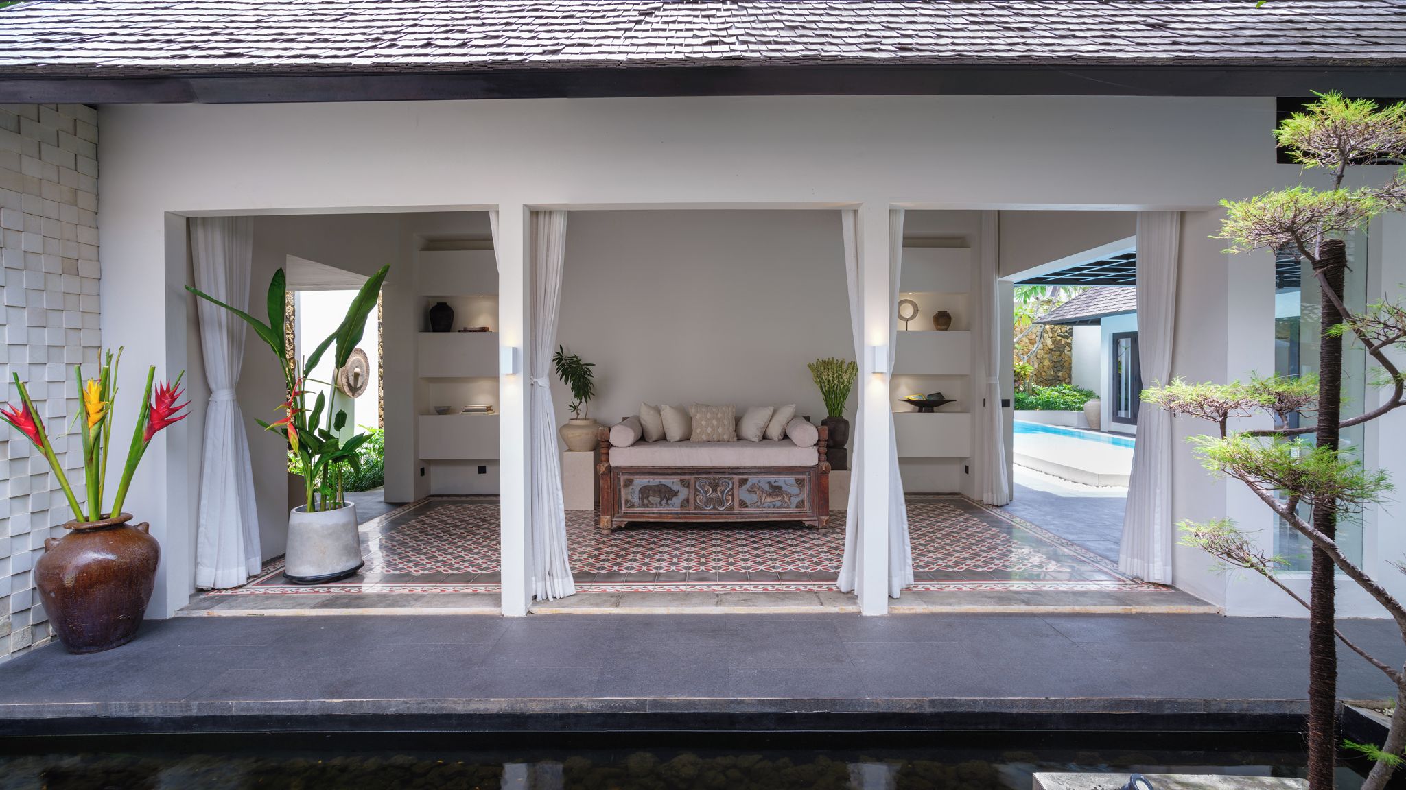 A modern interior with a sofa set, decorative plants, and a patterned floor.