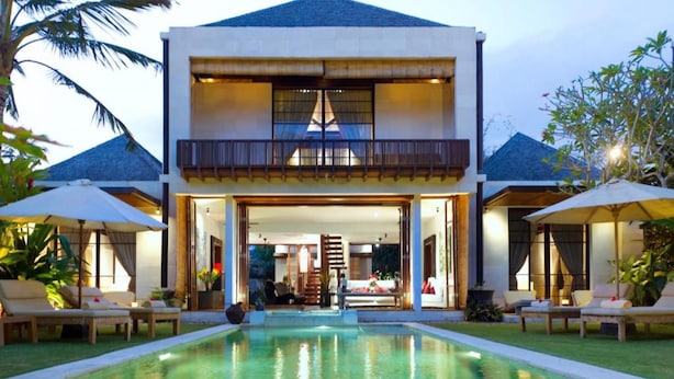 Una moderna casa a due piani con una piscina di fronte.