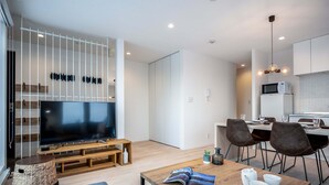 Un soggiorno moderno con televisore a schermo piatto, mobile TV in legno e zona pranzo con tavolo e sedie.
