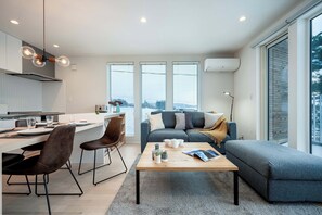 A modern living space with a kitchen, dining area, and a seating area with a view. - Arthouse by H2 Life (Furano)