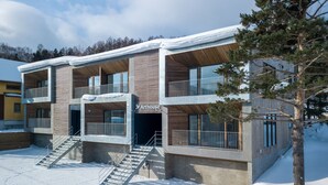 Un edificio moderno a più piani con facciata in legno, balconi e una scala che conduce all'ingresso.