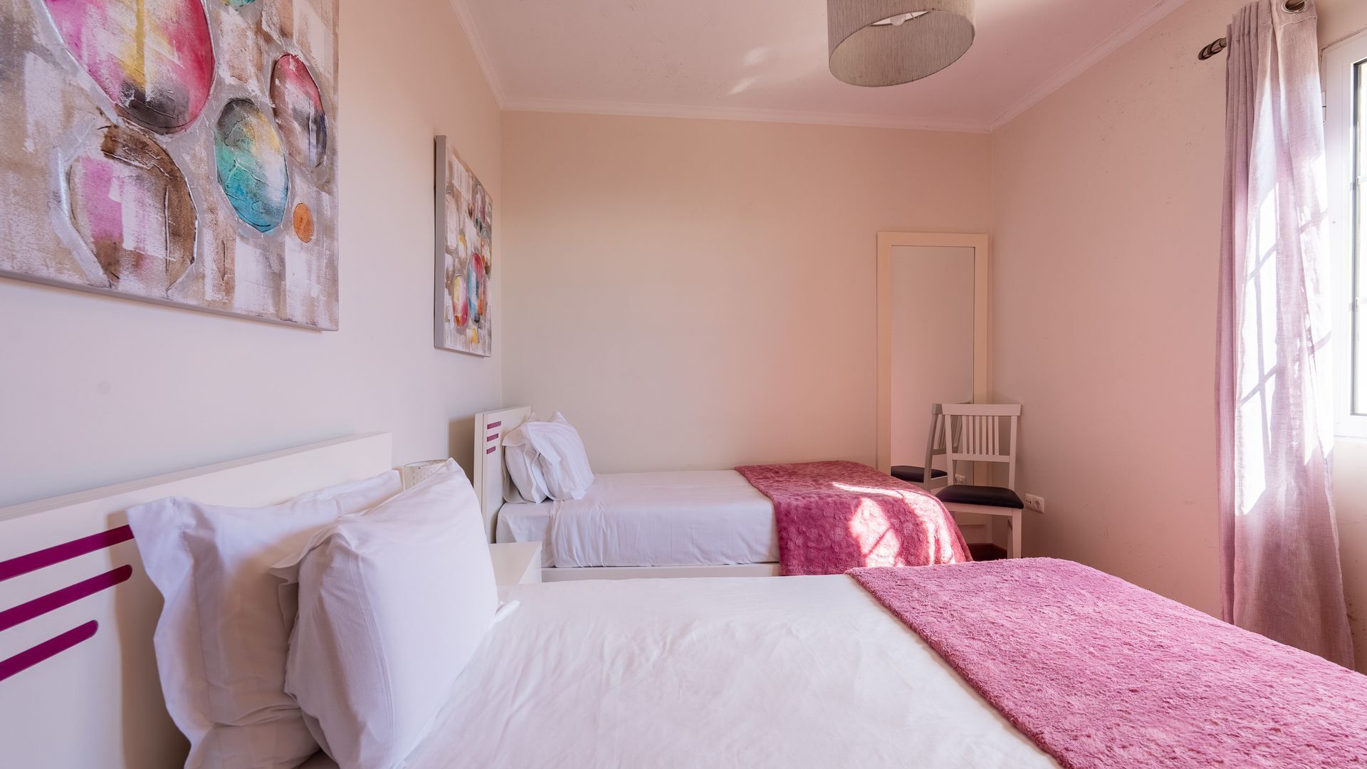 Ein Schlafzimmer mit zwei Betten, einem großen Spiegel und Bildern an den Wänden.