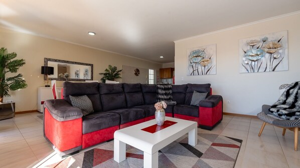 A living room with a sectional sofa, a coffee table, and two paintings on the wall.