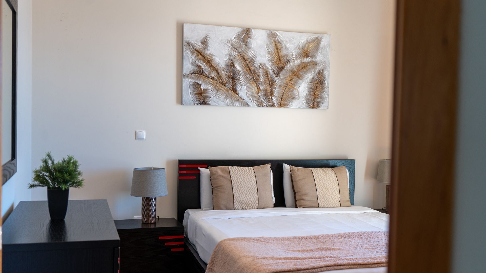 Une chambre d’hôtel comprenant un lit, une table de chevet, une lampe et une œuvre d’art accrochée au mur.