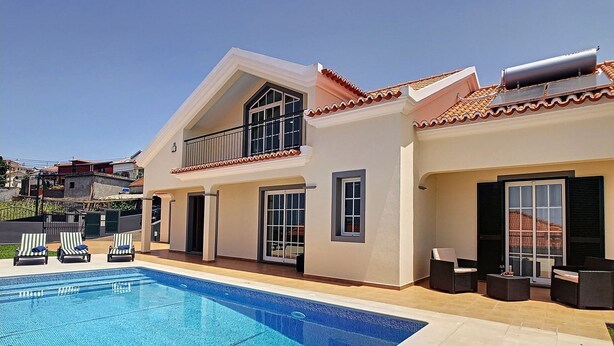 A two-story house with a swimming pool, outdoor seating, and a view of the neighborhood.