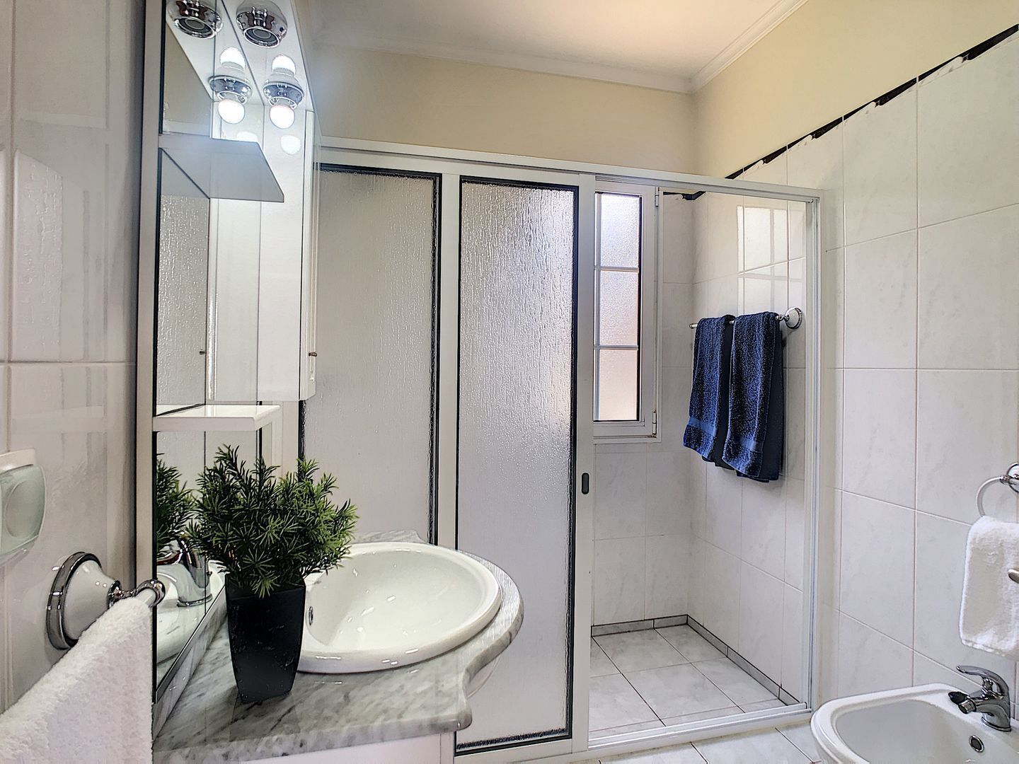 A bathroom with a shower, a sink, a mirror, and a towel rack.