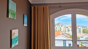 A room with a large window, a view of buildings, and three framed artworks on the wall. - Casa Ulli by LovelyStay (Canico)